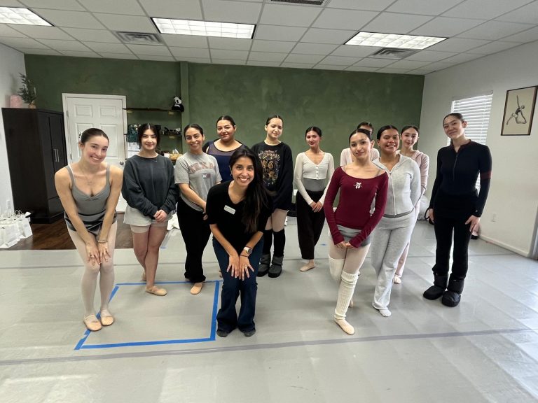 Dr. Mayra Navarrete standing with a group of dancers in a studio.
